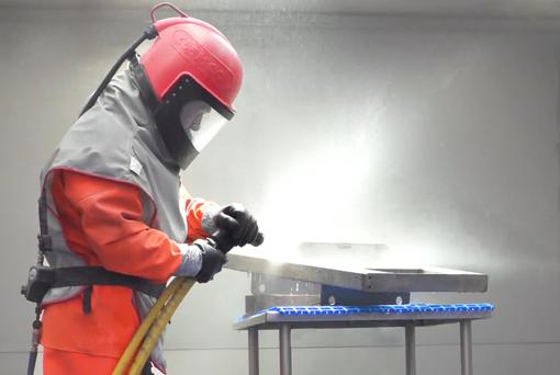 A worker uses an aqua blasting machine to finish 304 grade stainless steel for use in drum handling equipment.
