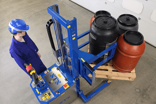 An STS drum handling machine lifting a black HDPE olive barrel from a full pallet.